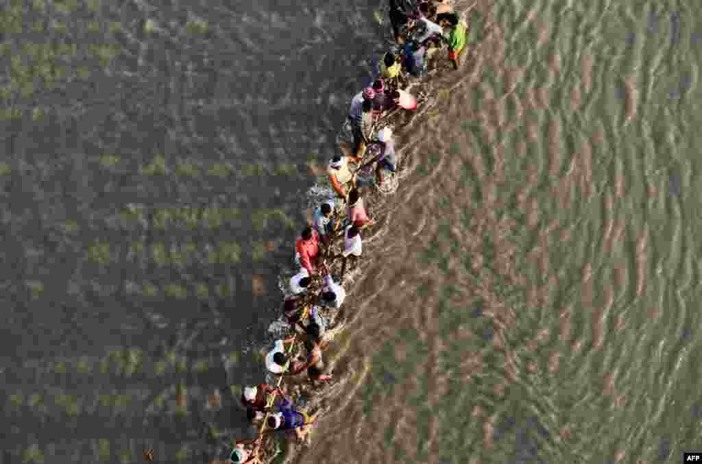 Laborers pull a pontoon buoy with a rope as they build a floating pontoon bridge over the River Ganges for the upcoming Kumbh Mela festival in Allahabad, India.