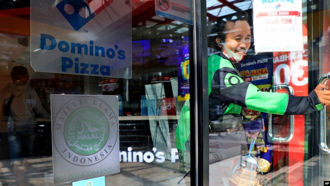 A man leaves as 'halal' logo of Indonesian Ulema Council is displayed on the facade of a restaurant in Jakarta, Indonesia, Wednesday, Nov. 11, 2020. As companies race to develop a COVID-19 vaccine and countries scramble to secure doses, questions…
