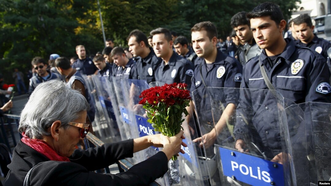 A demonstrator holds flowers before a police barricade during a commemoration for the victims of Saturday's bomb blasts in Ankara, Turkey, October 11, 2015.