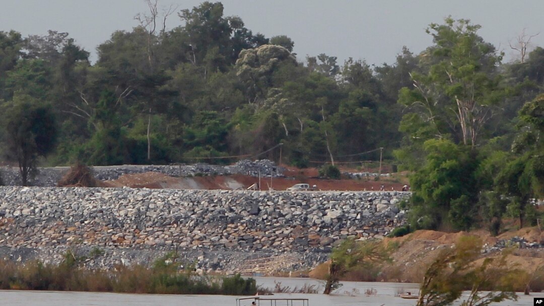 FILE - In this June 20, 2016 photo, a fishing boat passes near a construction site of the Don Sahong dam, near Cambodia-Laos borders, in Preah Romkel village, Stung Treng province, northeast of Phnom Penh, Cambodia.