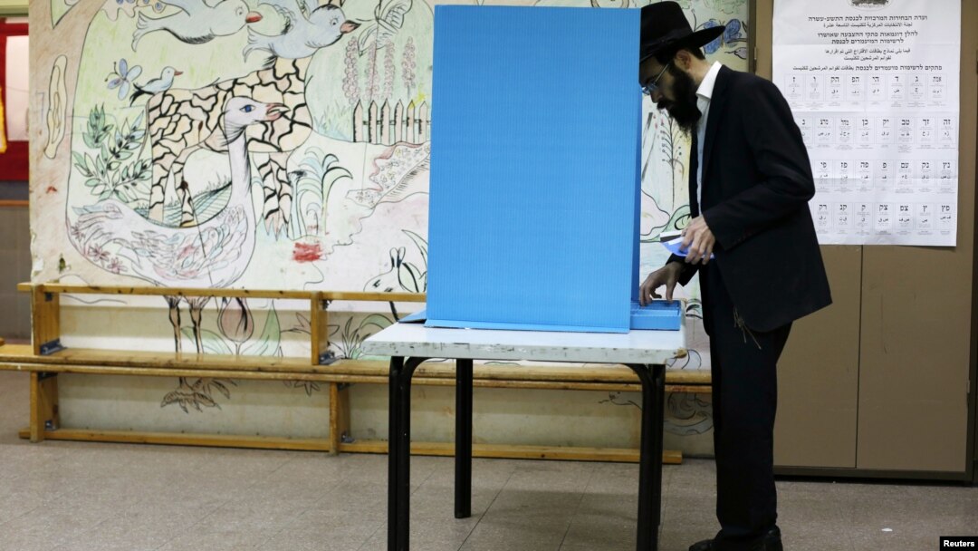 An ultra-Orthodox Jewish man stands near a booth at a polling station in the West Bank Jewish settlement of Kochav Ya'acov, north of Jerusalem, January 22, 2013. 