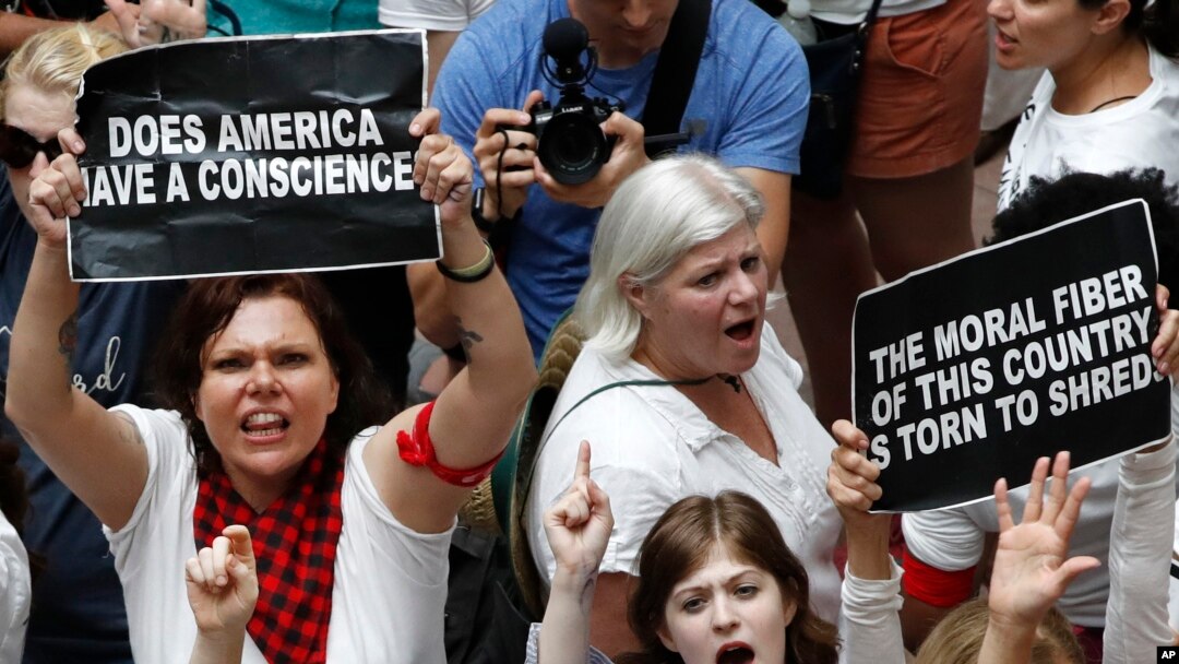 Women hold signs as they protest the separation of immigrant families, June 28, 2018, inside the Hart Senate Office Building on Capitol Hill in Washington.