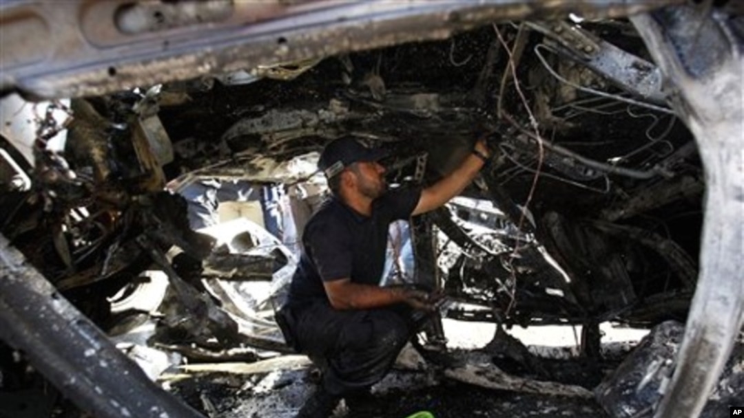 A Palestinian Hamas police officer examines a destroyed car after an explosion in Gaza City, 3 Nov. 2010.