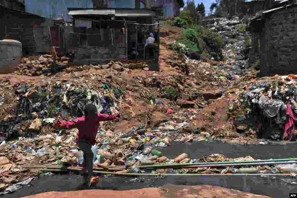 A young resident of Nairobi's Kibera slum, one of Africa's largest housing projects, crosses a heavily polluted section of the Ngong River in Kenya.