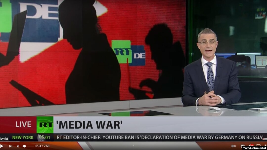 A presenter for the Russian state broadcaster RT delivers a report on YouTube's shutting down two of RT's German channels over alleged coronavirus misinformation in this screengrab from YouTube.