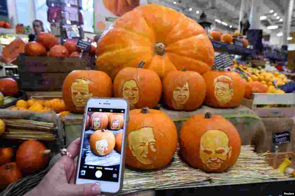 A woman takes a picture on her phone of Halloween pumpkins with Ireland's Presidential candidates faces carved into them in a shop ahead of an upcoming Presidential election in Dublin, Ireland.