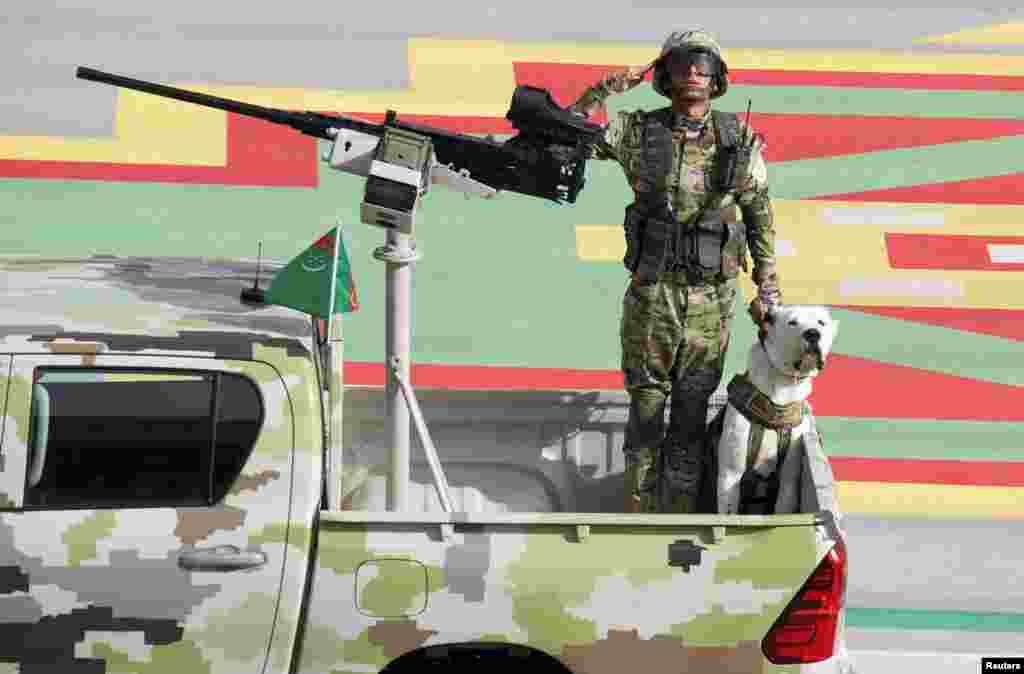 A soldier salutes as he rides with a dog in a pickup during a parade marking the Independence Day of Turkmenistan, in Ashgabat, Sept. 27, 2021.