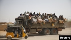 FILE - Migrants sit on their belongings in the back of a truck as it is driven through a dusty road in the desert town of Agadez, Niger, headed for Libya, May 25, 2015. 