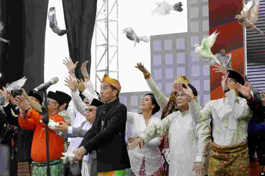 Indonesian President Joko Widodo, second left, and his running mate Ma'ruf Amin, left, and his contender Prabowo Subianto, second right, with his running mate Sandiaga Uno, right, release birds during a ceremony marking the kick off of the campaign period for next year's election in Jakarta.