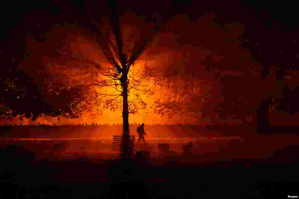 A man walks through a park during on a cold foggy at night in Athboy, Ireland, Oct. 31, 2018