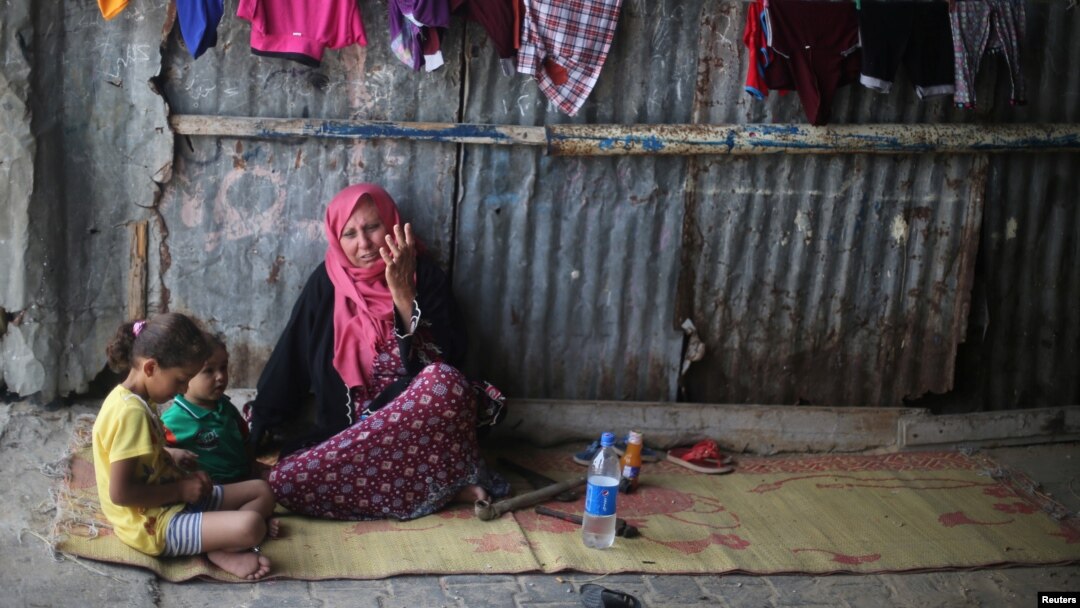 A Palestinian woman sits with her grandchildren in Khan Younis refugee camp in the southern Gaza Strip, July 11, 2017. 
