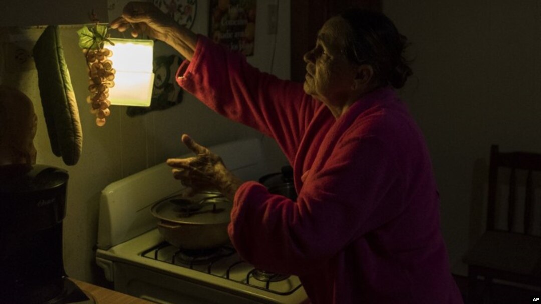 En esta imagen, tomada el 12 de julio de 2018, Marta Bermúdez Robles, de 66 años, cuelga una lámpara en su cocina, en Adjuntas, Puerto Rico, ante la falta de electricidad desde el paso de los huracanes Irma y María. 
