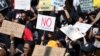 FILE - Women hold placards as they protest against gender-based violence, outside the Johannesburg Stock Exchange in Sandton, Johannesburg, South Africa, Sept. 13, 2019. 