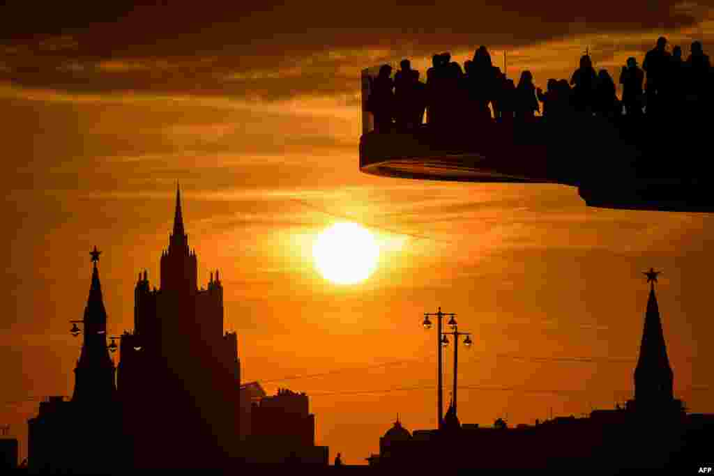 People enjoy the view from a pedestrian bridge in the newly-opened Zaryadye Park, with the Kremlin's towers and the main building of the Russian Foreign Ministry seen in the background, as the sun sets in downtown Moscow, Russia, Sept. 25, 2017.