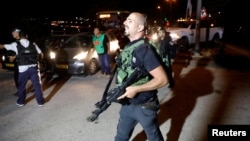 A security guard walks into the Israeli settlement Adam after a Palestinian assailant stabbed three people, one fatally, and then was shot and killed, according to the Israeli military, in the occupied West Bank, July 26, 2018. 
