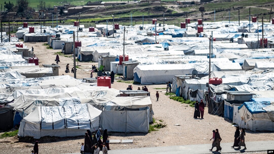 FILE - Women and children walk at Roj camp, where relatives of people suspected of belonging to the Islamic State group are held, in the countryside near al-Malikiyah in Syria's northeastern Hasakah province, on March 28, 2021.