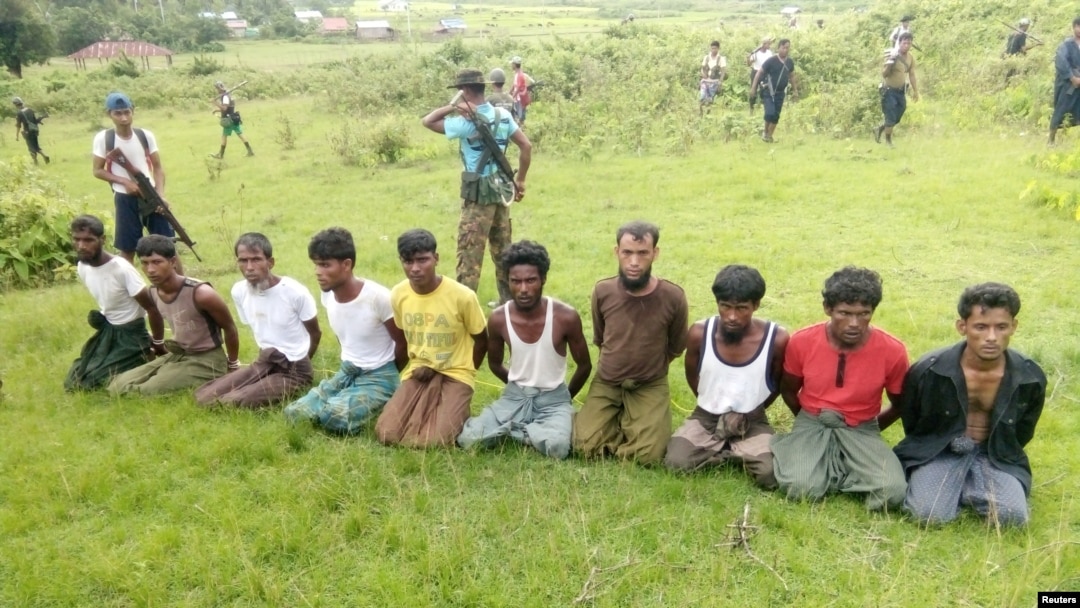 FILE - Ten Rohingya Muslim men with their hands bound kneel as members of the Myanmar security forces stand guard in Inn Din village, Sept. 2, 2017. 