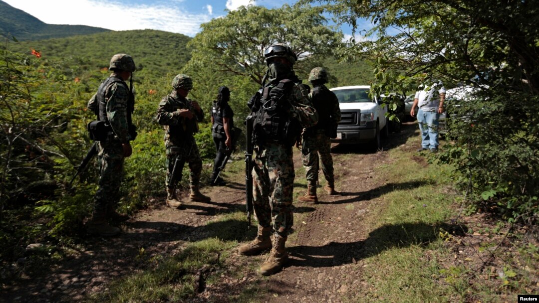 FILE - Soldiers guard an area where a mass grave was found, in Colonia las Parotas on the outskirts of Iguala, in Guerrero, Mexico.