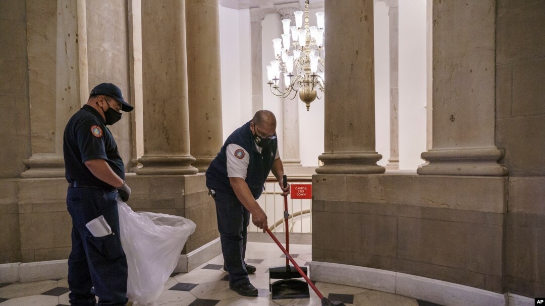 Trabajadores limpian los destrozos afuera de la oficina de la presidenta de la Cámara de Representantes de EE.UU. Nancy Pelosi, un día después del violento asalto al Capitolio por parte de seguidores del presidente Donald Trump. 7 de enero de 2021. 