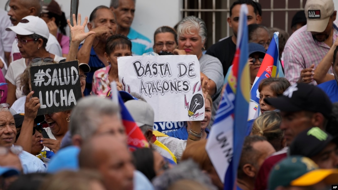 Un letrero de un manifestante antichavista en el que se lee "basta de apagones" es visto en medio de una concentración a favor del candidato presidencial opositor Edmundo González Urrutia en La Victoria, Aragua, el 18 de mayo de 2024.