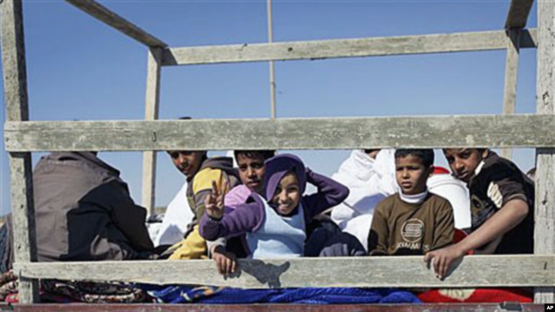 Children sit in the back of an open-air truck as they flee Brega during an exchange of fire with pro-Gadhafi forces, in Libya, April 4, 2011